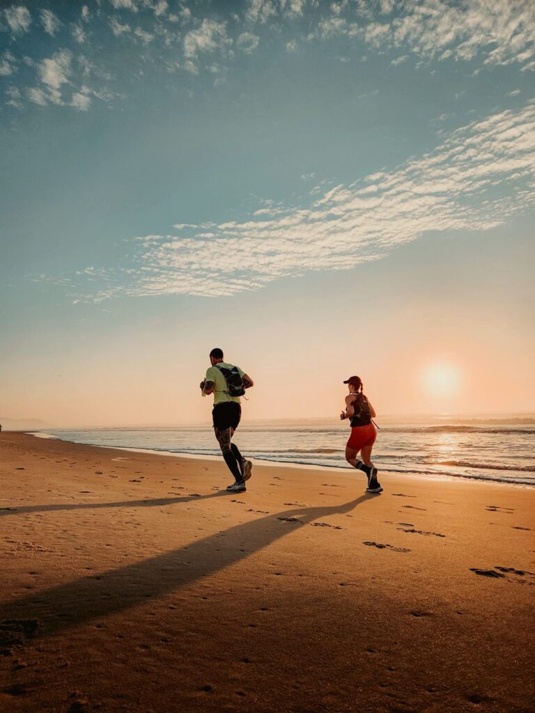 To løbere på en strand ved solopgang